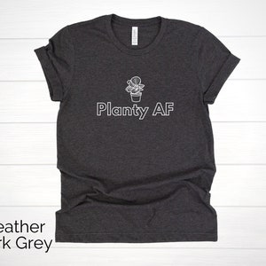 May include: Heather dark grey t-shirt with a white outline of a potted plant and the text "Planty AF".