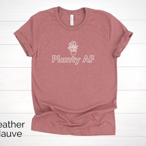 May include: Heather mauve t-shirt with a white outline of a potted plant and the text "Planty AF".