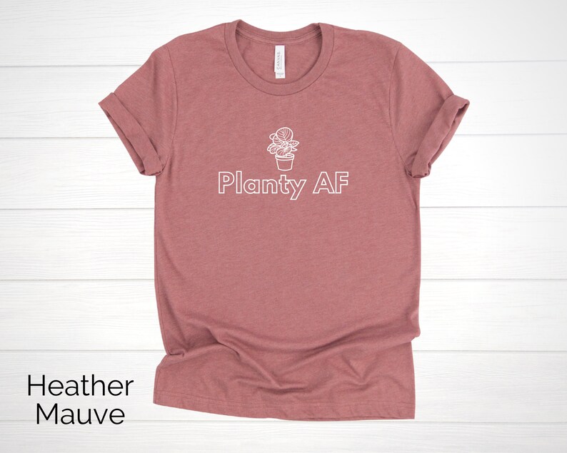 May include: Heather mauve t-shirt with a white outline of a potted plant and the text "Planty AF".