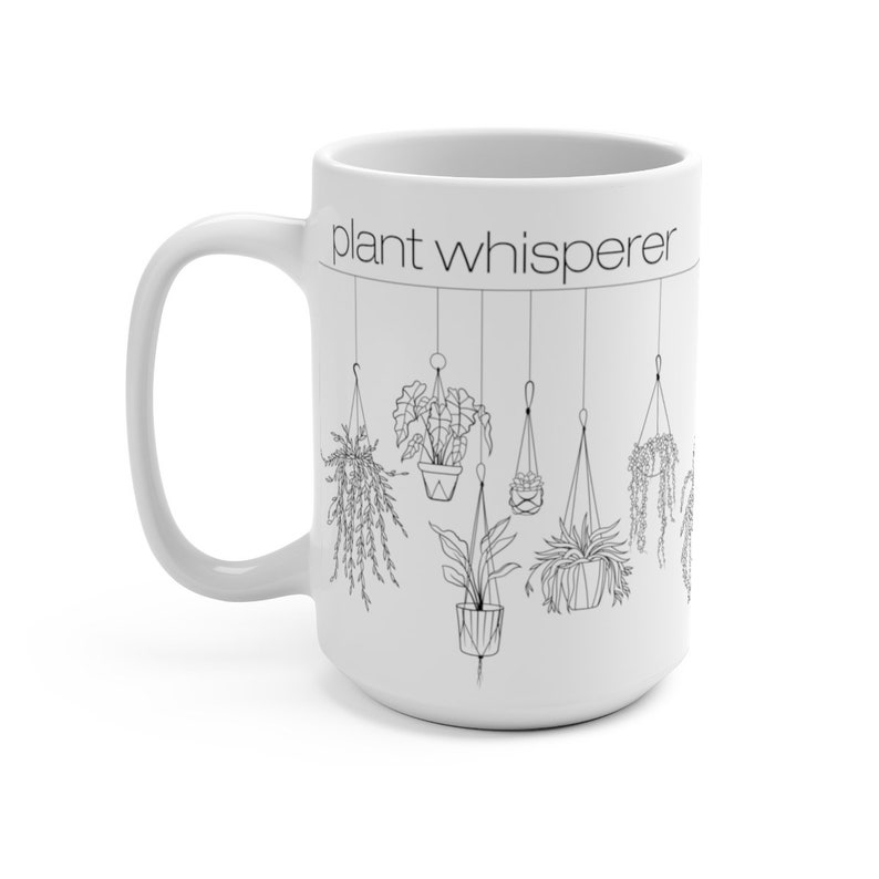 May include: White ceramic mug with a black outline of hanging plants and the text "plant whisperer".