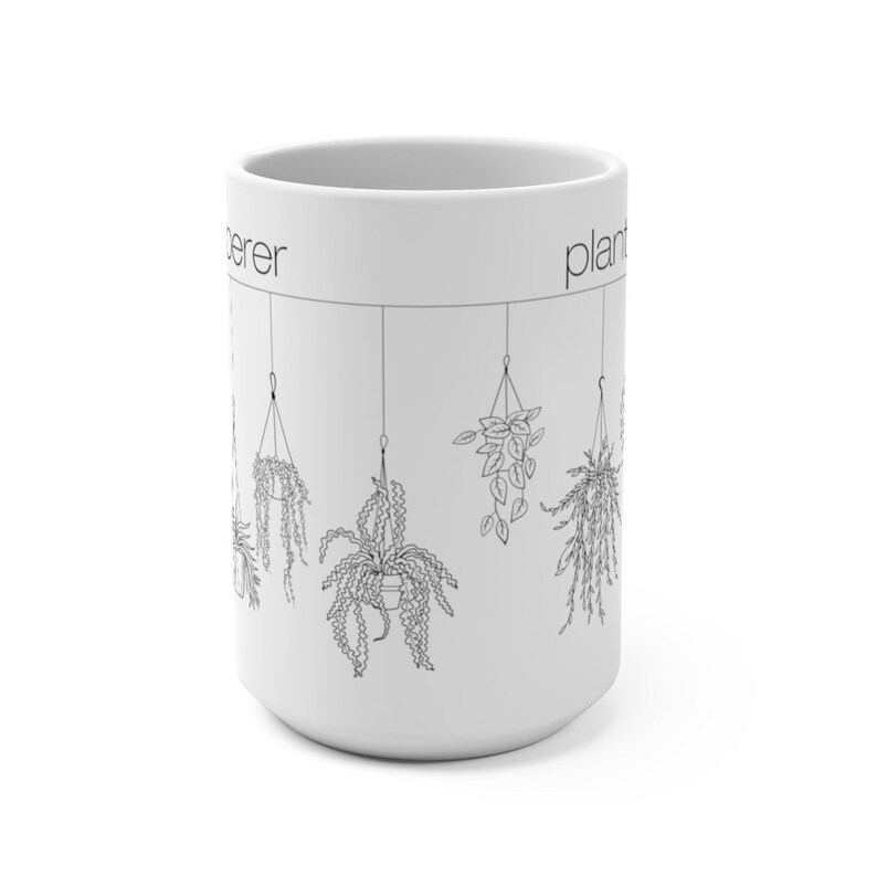 May include: White ceramic mug with a black outline of hanging plants and the text "plant lover" on the right side and "lover" on the left side.