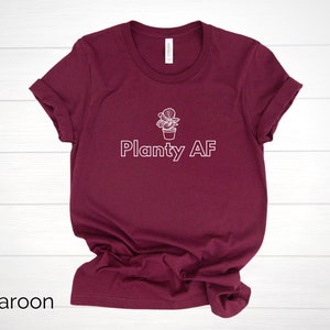 May include: A maroon t-shirt with a white outline of a potted plant and the text "Planty AF".