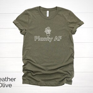 May include: A heather olive t-shirt with a white graphic of a potted plant and the text "Planty AF".