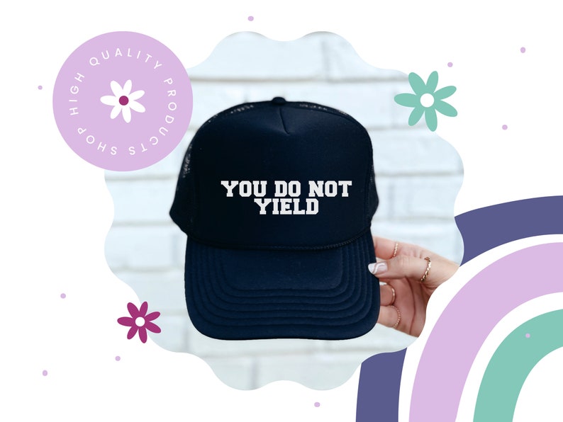 K&ouml;nnte beinhalten: Eine marineblaue Trucker-M&uuml;tze mit dem Text "YOU DO NOT YIELD" in wei&szlig;en Blockbuchstaben. Die M&uuml;tze hat eine Netzr&uuml;ckseite und einen gebogenen Schirm. Ein kreisf&ouml;rmiges Logo mit dem Text "HIGH QUALITY PRODUCTS SHOP" befindet sich in der oberen linken Ecke.