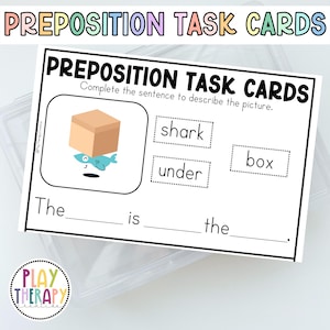 May include: A white task card with the text "PREPOSITION TASK CARDS" and a cartoon illustration of a box and a shark. The card includes fill-in-the-blank sentences to describe the picture. The words "shark", "under", and "box" are also included.