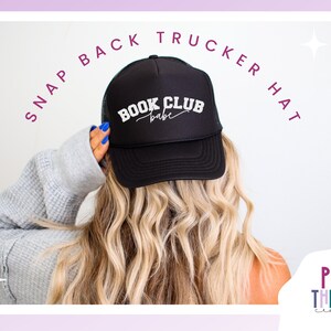 Peut inclure: Casquette de camionneur noire avec un texte blanc qui dit "Book Club Babe" en &eacute;criture cursive. La casquette est port&eacute;e par une personne aux longs cheveux blonds.