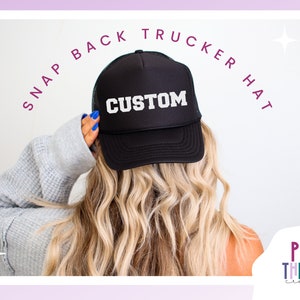 Może przedstawiać: Czarna czapka typu trucker z zapięciem zatrzaskowym z napisem "CUSTOM" w białych literach. Czapka ma siatkowy tył i zakrzywiony daszek. Tekst "SNAP BACK TRUCKER HAT" jest wygięty nad czapką. Obraz zawiera r&oacute;wnież logo "PLAY THERAPY creative".