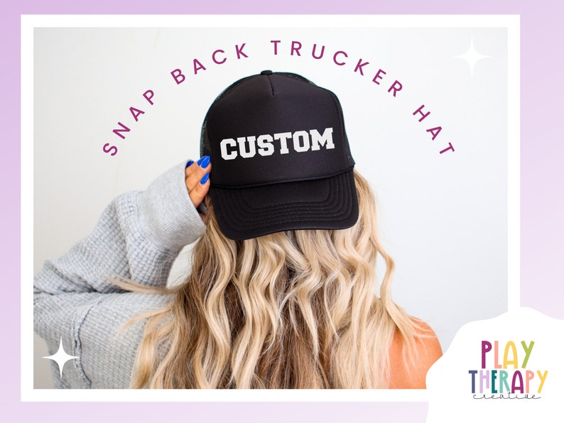 Może przedstawiać: Czarna czapka typu trucker z zapięciem zatrzaskowym z napisem "CUSTOM" w białych literach. Czapka ma siatkowy tył i zakrzywiony daszek. Tekst "SNAP BACK TRUCKER HAT" jest wygięty nad czapką. Obraz zawiera r&oacute;wnież logo "PLAY THERAPY creative".