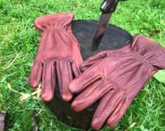 May include: A pair of brown leather gloves with a textured surface. The gloves are laid out on a wooden surface.
