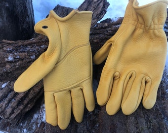 May include: A pair of yellow leather work gloves with a reinforced palm and fingers. The gloves are laid out flat on a wooden surface.