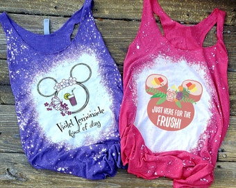 May include: Two bleached tank tops with a Mickey Mouse silhouette design. The purple tank top has a glass of lemonade with flowers and a butterfly. The text reads "Violet Lemonade kind of day". The pink tank top has a sushi roll with flowers and the text reads "Just here for the FRUSHI".