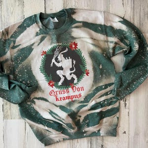 May include: A green and white tie-dye sweatshirt with a black and white illustration of a Krampus figure with the text "Gruss Von Krampus".
