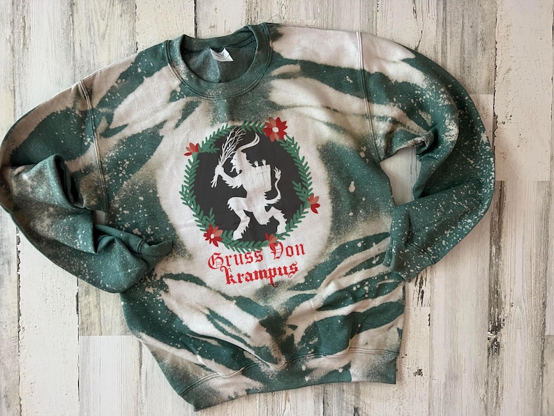 May include: A green and white tie-dye sweatshirt with a black and white illustration of a Krampus figure with the text "Gruss Von Krampus".