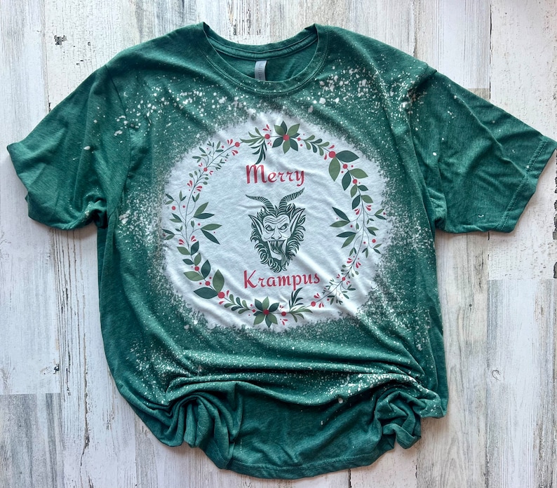 May include: Green t-shirt with a white bleach design of a wreath with the words "Merry Krampus" and a cartoon Krampus inside.