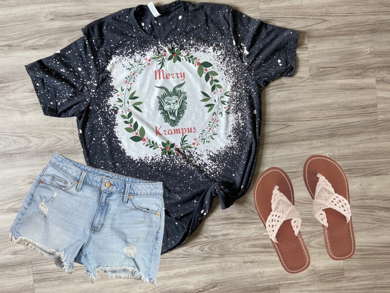 May include: Black t-shirt with a white bleach design of a wreath with the words "Merry Krampus" and a green monster face inside.
