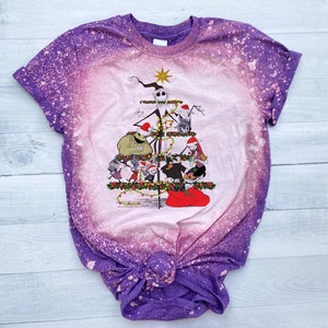 May include: A purple and white tie-dye t-shirt with a bleach-splattered design. The shirt features a graphic of characters from the Nightmare Before Christmas movie, arranged in a Christmas tree shape.