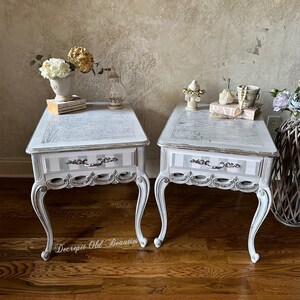 White nightstand with silver accents and stripped drawer. The top has this beautiful design with cursive writings that makes it unique.