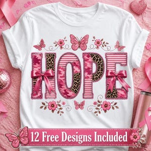 Op de afbeelding: Een wit t-shirt met korte mouwen en het woord HOPE in grote letters met roze camouflage-, luipaard- en strepenpatronen. Het ontwerp bevat roze strikken, vlinders en bloemen, met een banner met de tekst 12 Free Designs Included.