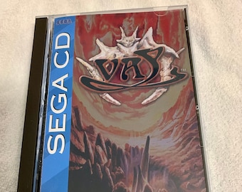 May include: A Sega CD game case with a red, orange and yellow background. The game title "Vay" is written in a stylised font. The game is rated MA-13 by the V.R.C. and is licensed by Sega Enterprises, Ltd. for play on the Sega CD system.