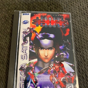 May include: A Sega Saturn video game case with a colorful image of characters from the game Burning Rangers. The case is black with a clear plastic cover and the title of the game is printed in white letters on a red background. The game is rated E for Everyone by the ESRB.