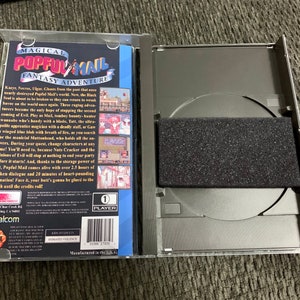 May include: An open, clear plastic case containing a Popful Mail Sega CD game. The game's cover art features the title "Magical Popful Mail Fantasy Adventure" with character illustrations. The CD is visible inside the case, along with a black foam insert.