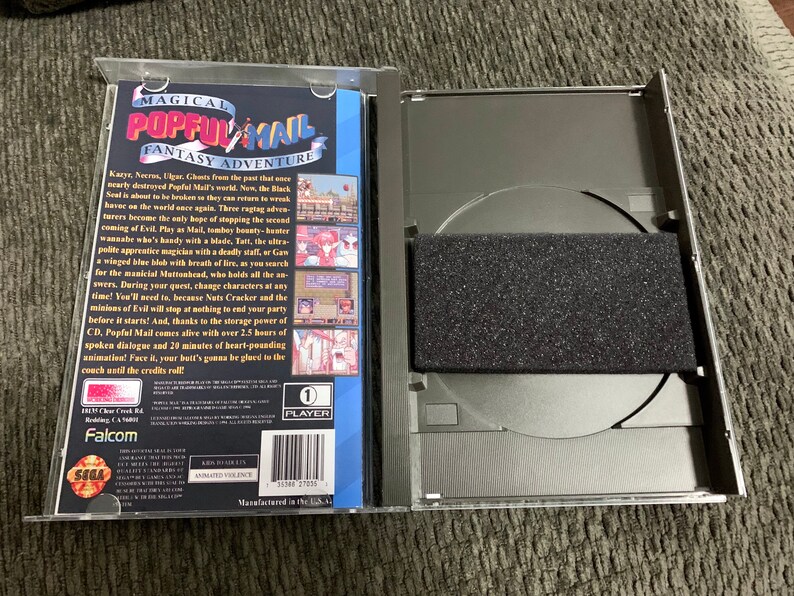 May include: An open, clear plastic case containing a Popful Mail Sega CD game. The game's cover art features the title "Magical Popful Mail Fantasy Adventure" with character illustrations. The CD is visible inside the case, along with a black foam insert.