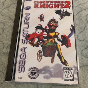 May include: A Sega Saturn video game case for Clockwork Knight 2. The case is white with a colorful image of the game's characters. The game is rated "KA" for Kids to Adults by the ESRB.