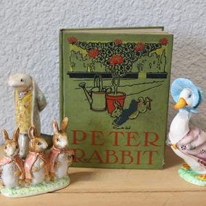 May include: A collection of Beatrix Potter figurines, including Peter Rabbit, Mrs. Tiggy-Winkle, and Jemima Puddle-Duck. The figurines are arranged in front of a book titled "Peter Rabbit".