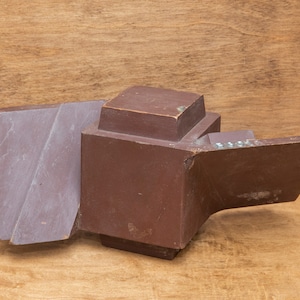 May include: A brown wooden model of a propeller, with a square base and a curved blade. The model is made of wood and has a dark brown finish.