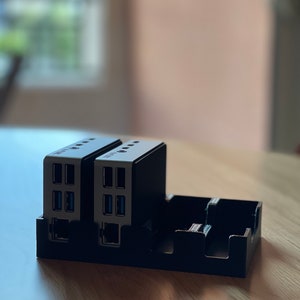 May include: Two black and silver USB hubs with multiple ports, including ethernet, are plugged into a black plastic stand.