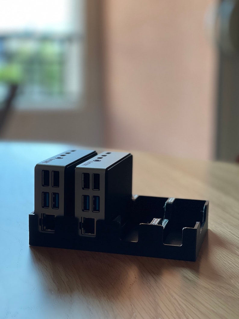 May include: Two black and silver USB hubs with multiple ports, including ethernet, are plugged into a black plastic stand.