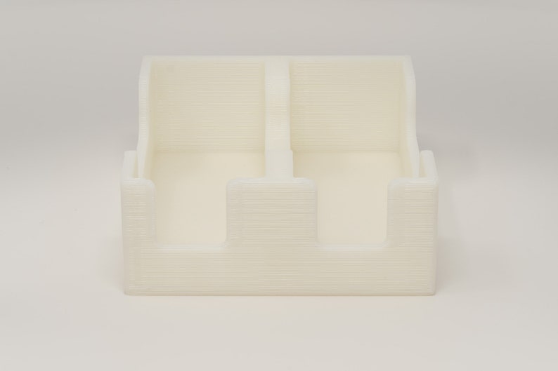 May include: A white plastic organizer with three compartments. The organizer is designed to hold small items, such as pens, pencils, or other office supplies.