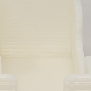 May include: Close-up of a white plastic object with a textured surface. The object has a rectangular shape with two open sides. The object is likely a 3D printed model.