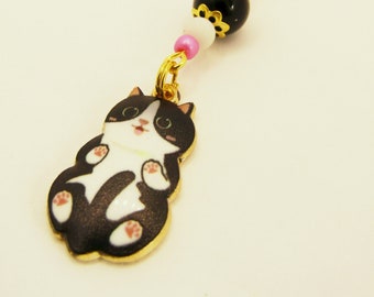 May include: A black and white cat charm with pink and white beads and a gold clasp. The charm is attached to a gold chain.