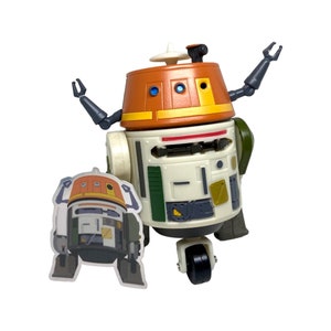 Op de afbeelding: Een wit, oranje en groen robot speelgoed met scharnierende armen en een enkel wiel. De robot heeft een sticker van een vergelijkbare robot aan de zijkant.