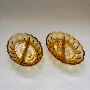 May include: Two amber glass divided serving dishes with a scalloped edge and a raised, textured design.