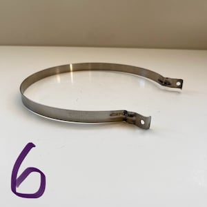 以下が含まれることがあります： 両端にタブが付いた銀色の金属バンド。バンドには「STAINLESS」の刻印があります。