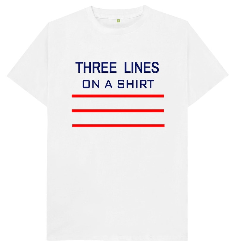 May include: White t-shirt with the text "THREE LINES ON A SHIRT" in navy blue and three red horizontal lines.