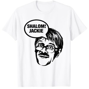 Può includere: T-shirt bianca con un'illustrazione in bianco e nero di un uomo con occhiali e baffi. Una nuvoletta sopra la testa dell'uomo dice "SHALOM! JACKIE". La grafica è centrata sulla parte anteriore della maglietta.