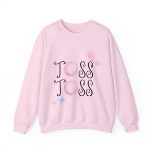 May include: Pink sweatshirt with the words "TOSS TOSS" in black lettering and a graphic of iridescent bubbles.