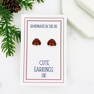 May include: A pair of brown dog-shaped stud earrings on a white card with the text "Handmade in the UK" and "Cute Earrings UK".