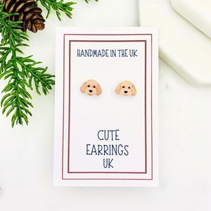 May include: A pair of cute dog-shaped earrings on a white card with the text "Handmade in the UK" and "Cute Earrings UK".