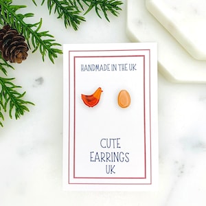 May include: A pair of cute earrings featuring a red and orange chicken and a brown egg. The earrings are handmade in the UK.