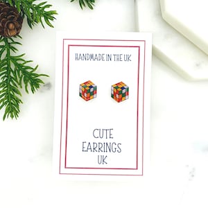 May include: A pair of colourful cube-shaped earrings on a white card with the text "HANDMADE IN THE UK" and "CUTE EARRINGS UK".
