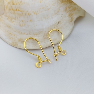 Può includere: Due ganci per orecchini dorati con chiusura a molla. I ganci sono in metallo e sono progettati per essere utilizzati con gli orecchini.