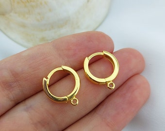 以下が含まれることがあります： 金色の円形のイヤリング留め具が2つ。各留め具はヒンジ付きの開口部と下部に小さなループが付いています。