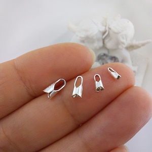 May include: Four silver-toned crimp end bead caps of varying sizes. The caps are designed to be used for jewelry making.