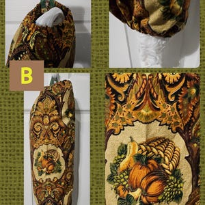 May include: A brown and gold fabric bag holder with a fall harvest print featuring pumpkins, gourds, and grapes. The bag holder is hanging on a white door.