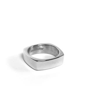 Könnte beinhalten: Ein silberner quadratischer Ring mit abgerundeten Kanten.