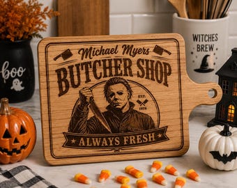 May include: A rectangular wooden cutting board with a handle, featuring a laser-engraved illustration of Michael Myers holding a knife. The text reads Michael Myers BUTCHER SHOP EST. 1978 and ALWAYS FRESH, surrounded by a decorative border.